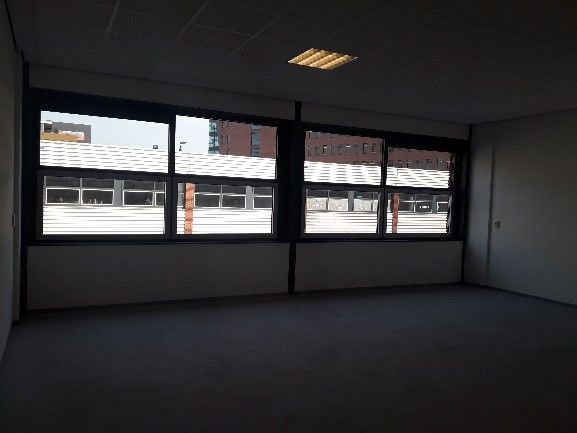 Leeg kantoor met grote ramen die uitkijken op de omliggende gebouwen.