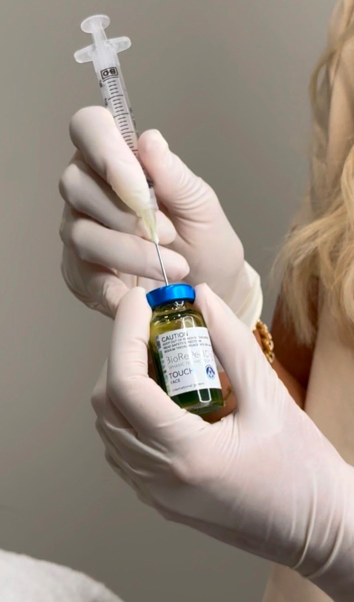 A Woman is Holding a Syringe and a Bottle of Liquid — Gorjess Aesthetics in Corrimal, NSW