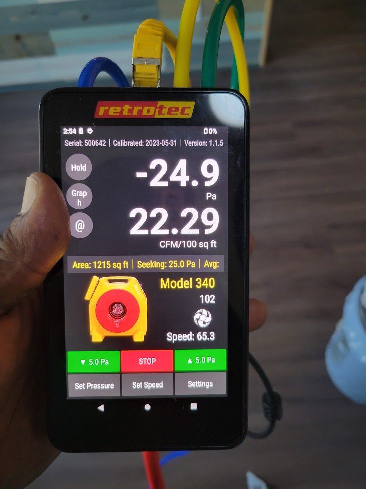 Hand holding a smartphone displaying a thermal camera app with large temperature readings and a yellow heat map thumbnail.