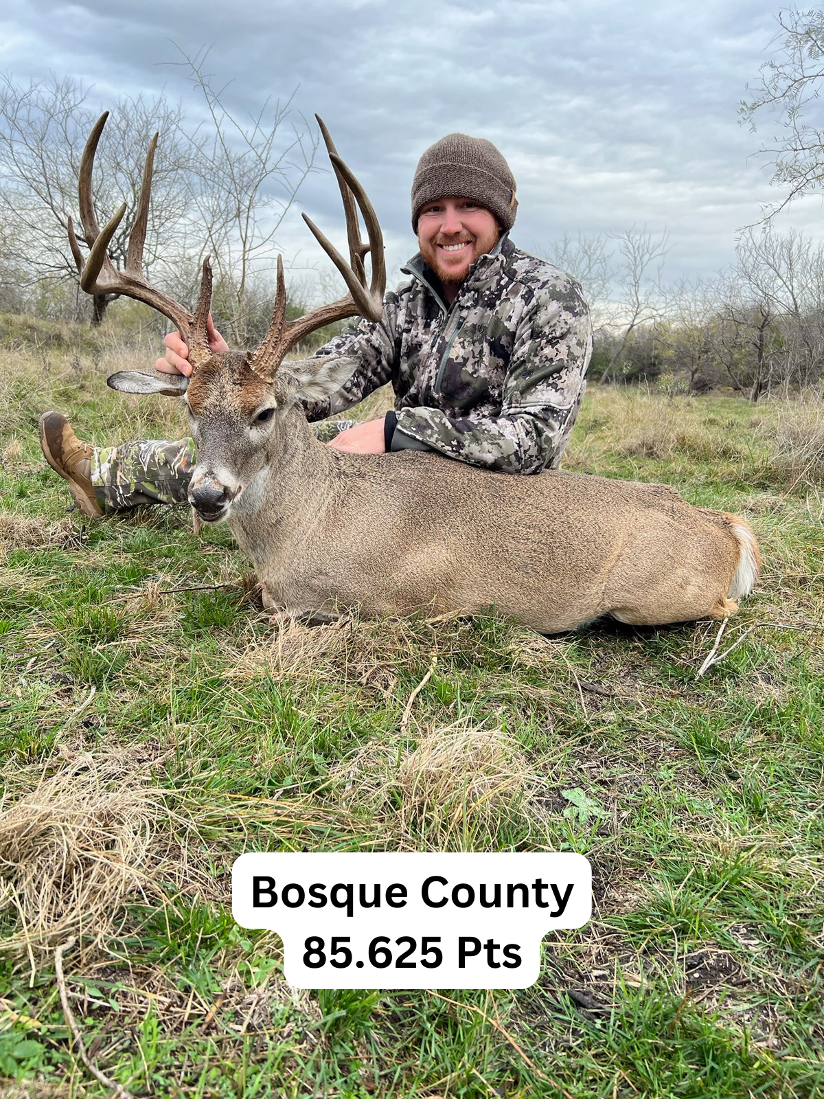 Man smiles, posing with a large deer he hunted in Bosque County, Texas.