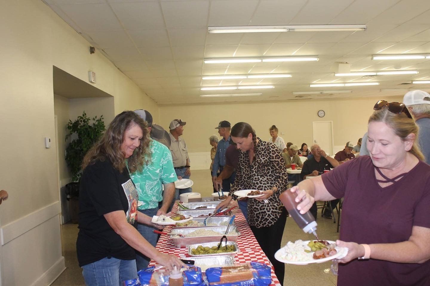 A group of people are standing around a table eating food.