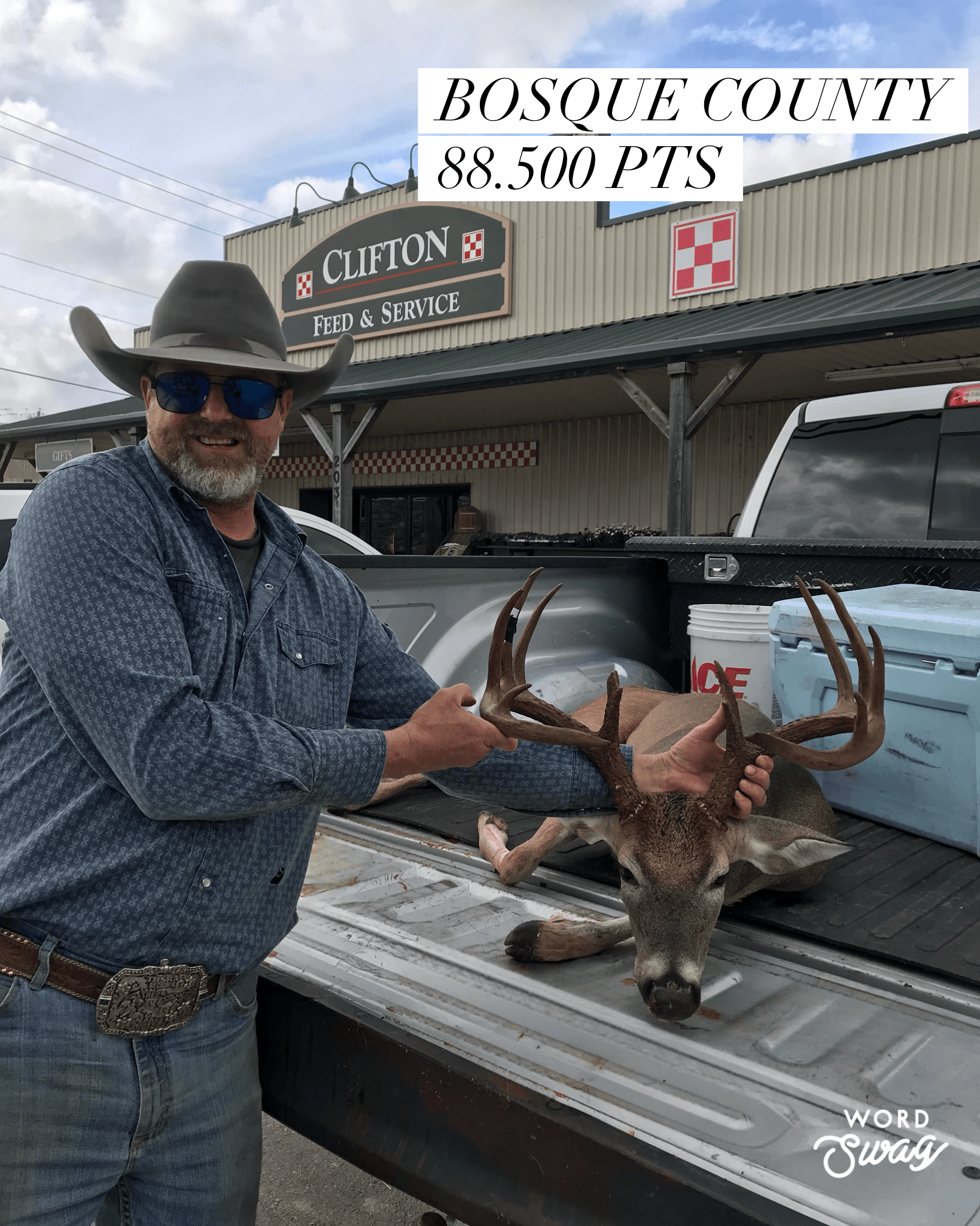 Man in cowboy hat with a deer buck on a truck bed, in front of a store in Bosque County.