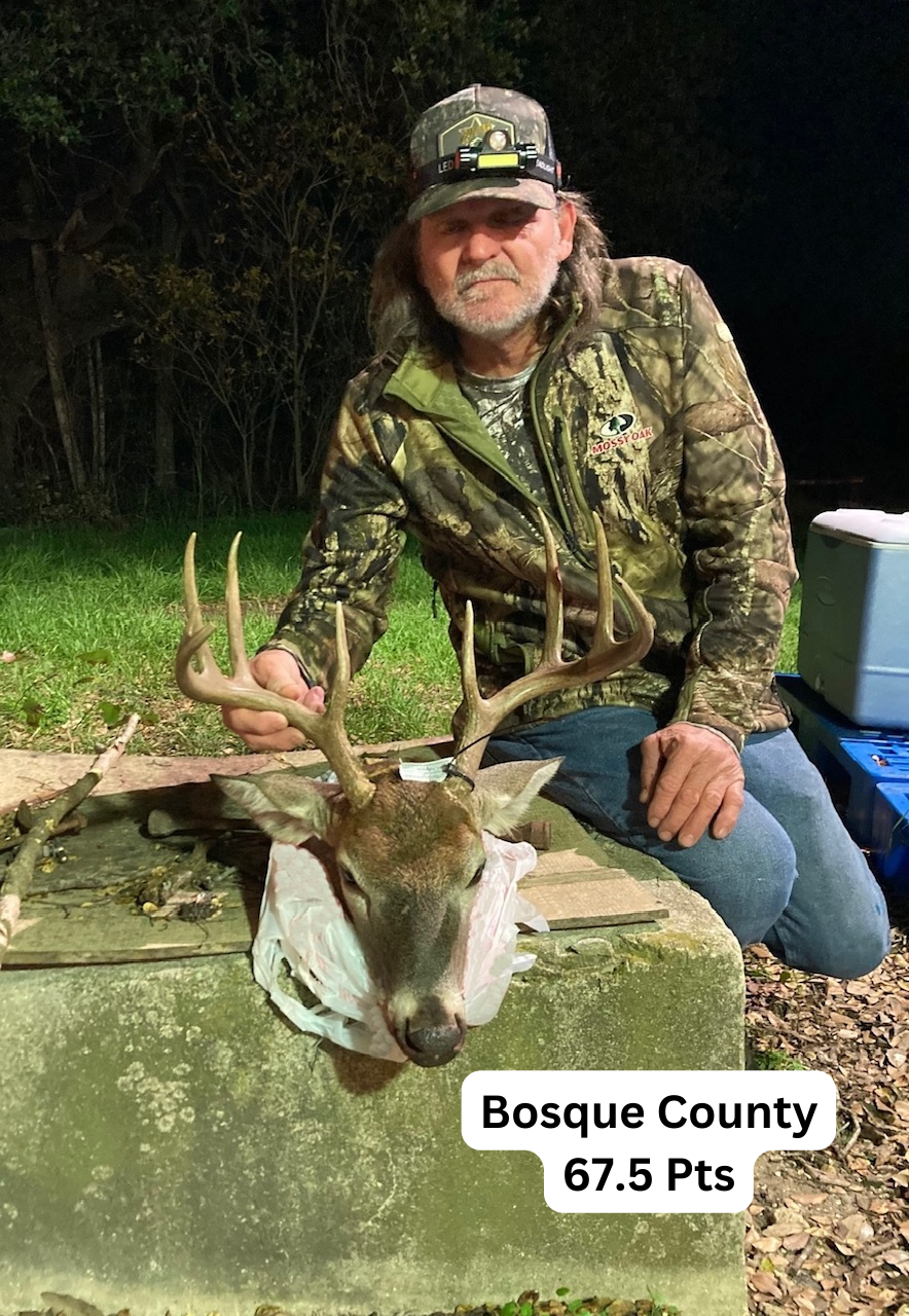 A man in a camouflage jacket is kneeling down next to a deer.