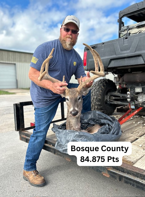 A man is holding a deer in front of a truck.