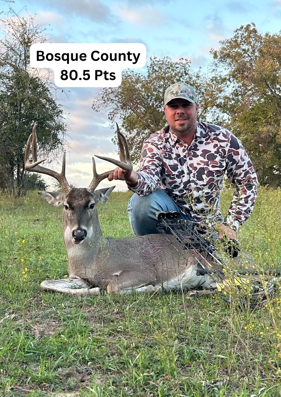 A man is kneeling next to a deer in a field.