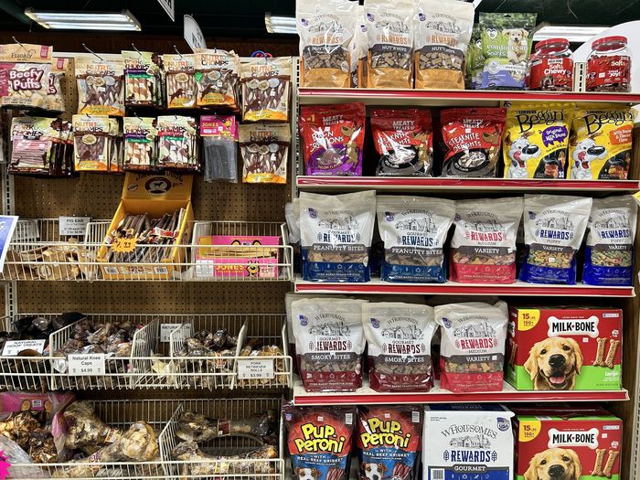 There are many different types of dog food on the shelves in this store.