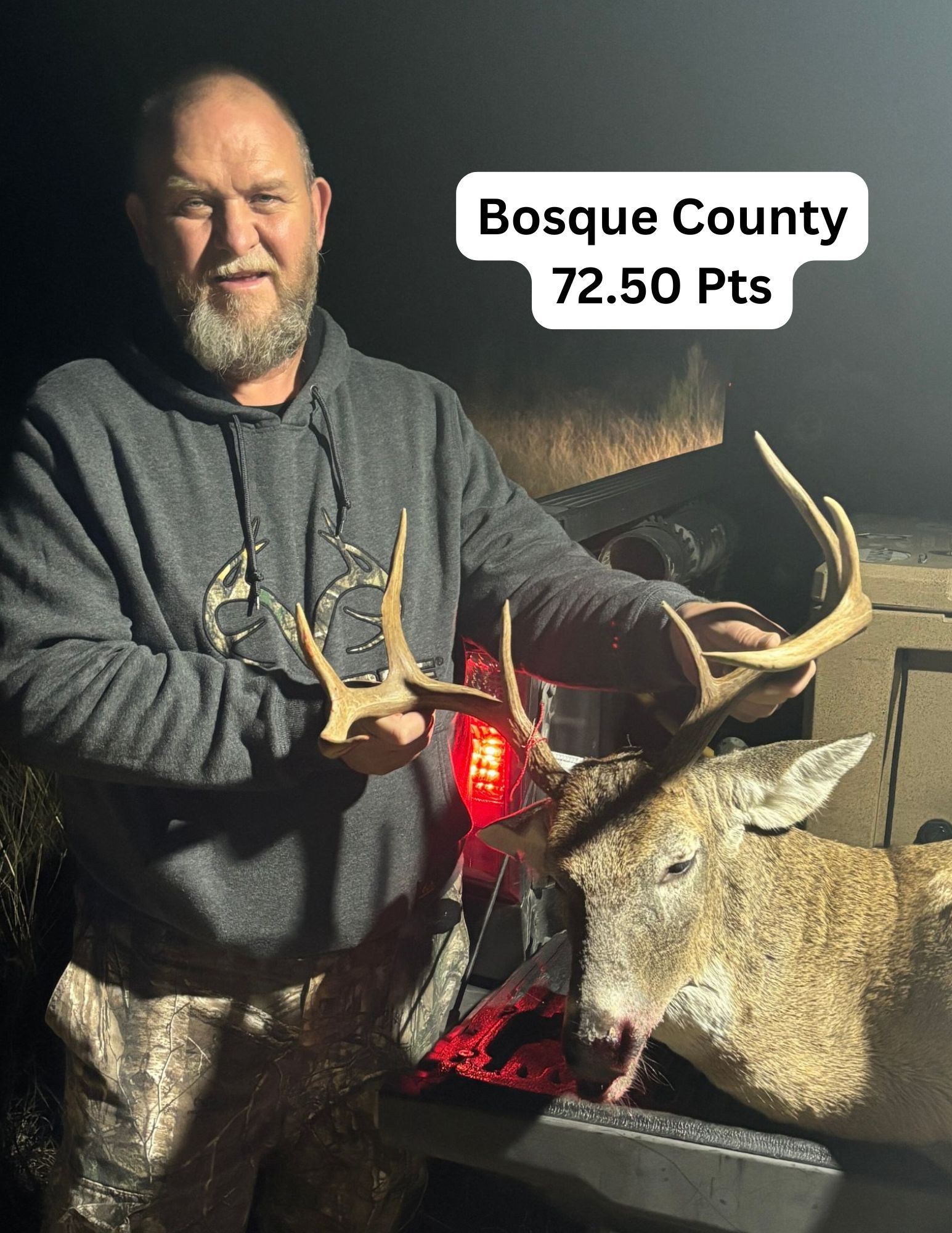 Man holding a deer he hunted in Bosque County, Texas. The deer has antlers. The man is smiling.