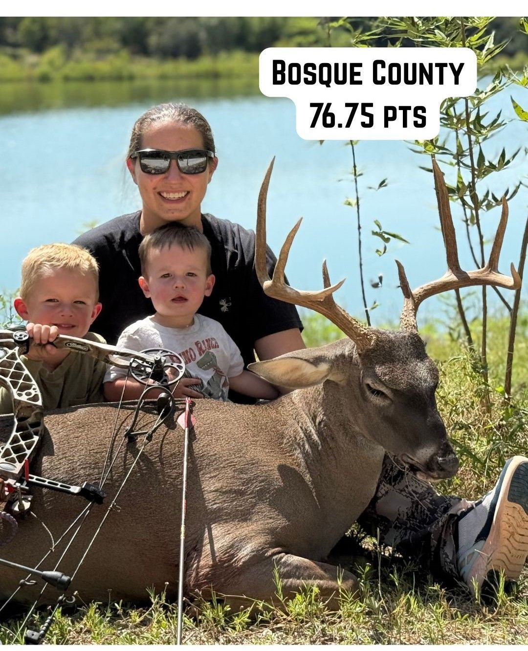 Woman and two children with deer, bow and arrow, lake in background, Bosque County.