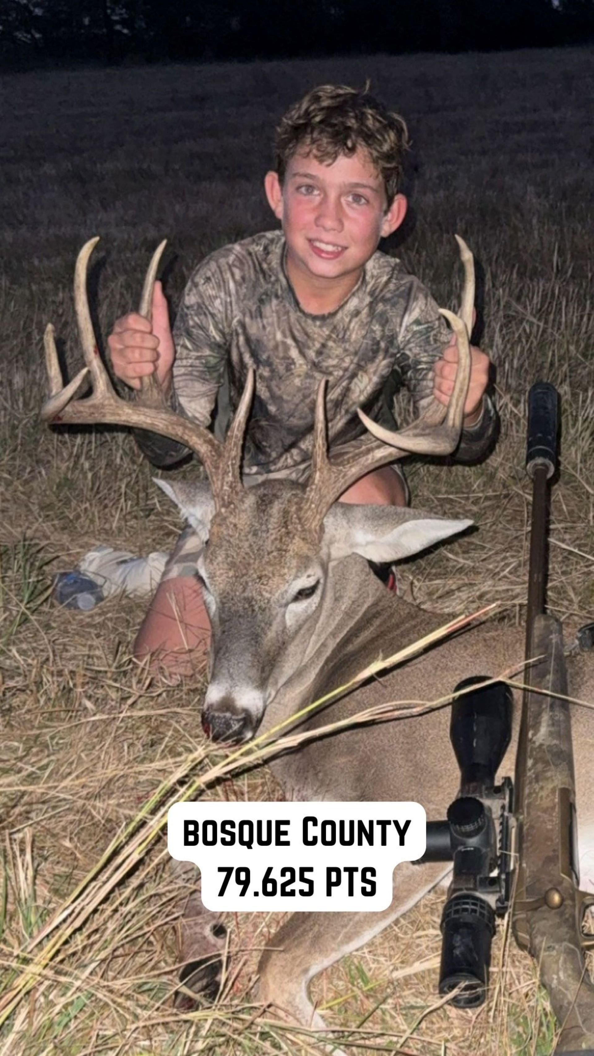 Boy smiles, giving thumbs-up next to a large buck he harvested in Bosque County, Texas. Rifle and scope present.