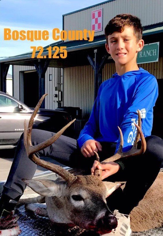 Boy in blue shirt with deer he hunted in Bosque County.