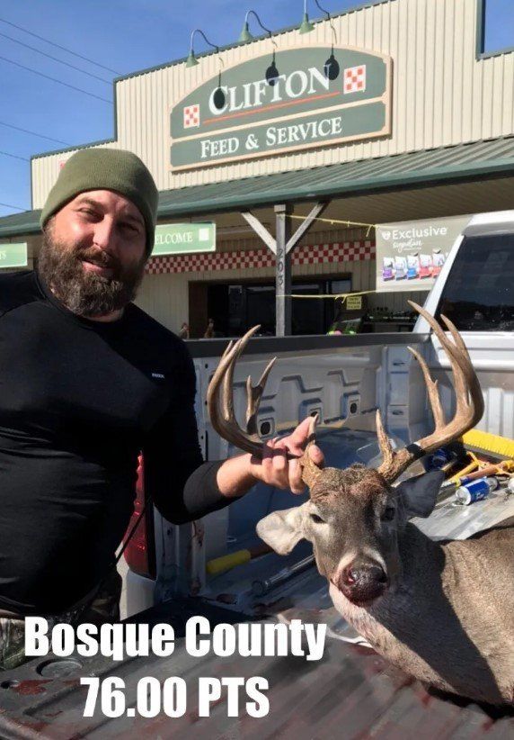 A man is holding a deer in front of a clipton store