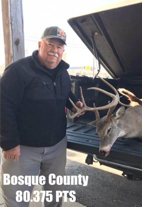 Man with a mustache smiles next to a buck in a truck bed. Bosque County, 80.375 PTS.