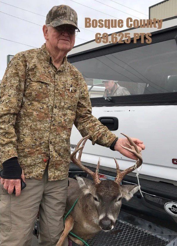 Man in camo holds deer in Bosque County. The deer has antlers. Score: 69.625 PTS.