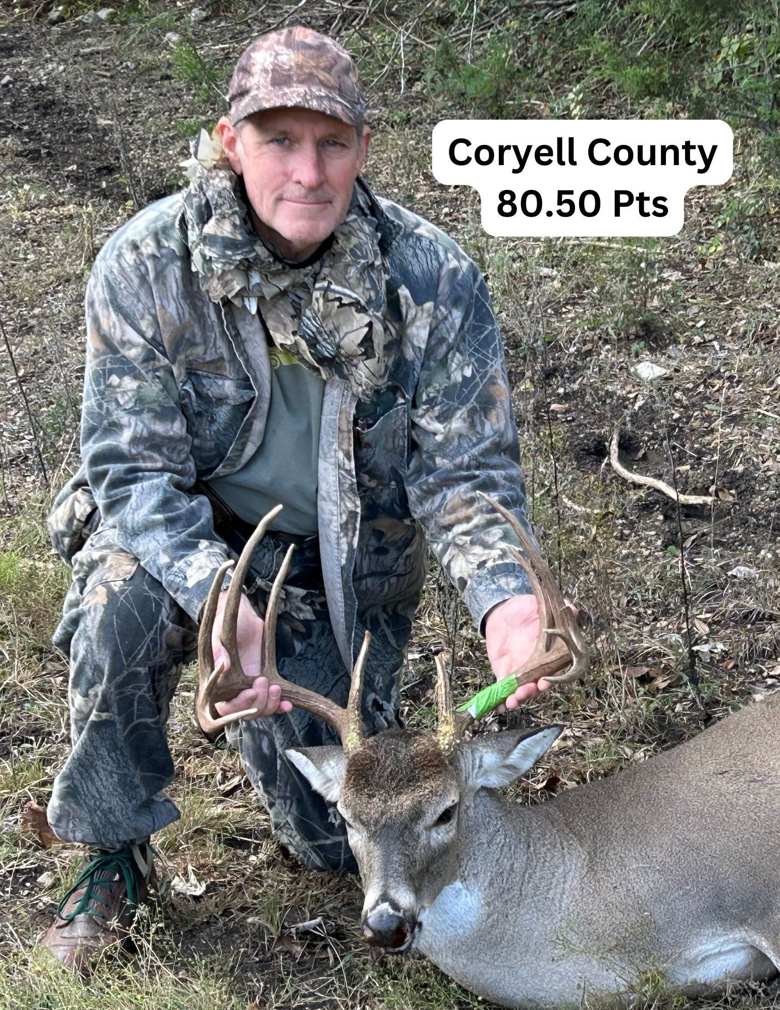 Hunter kneeling with a deer, Coryell County, Texas. Camo clothing, holding antlers, 80.50 points.