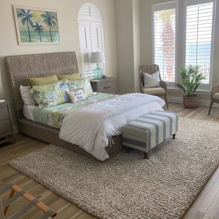 A bedroom with a bed and a striped ottoman