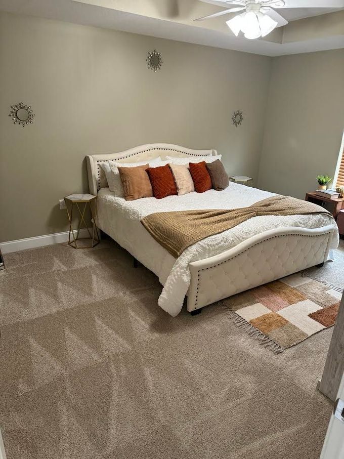 A bedroom with a king size bed and a ceiling fan.