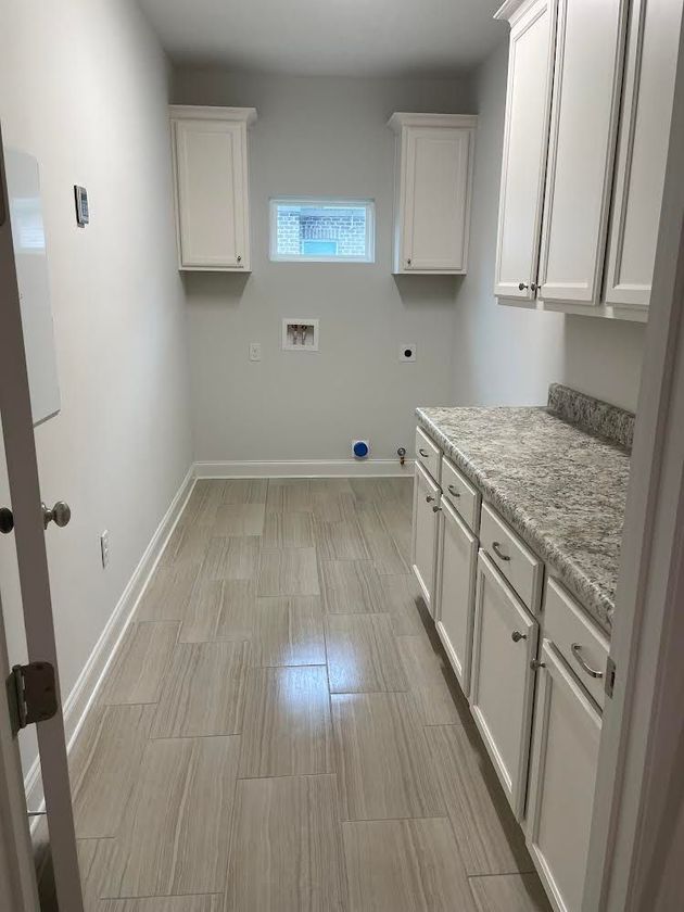 A laundry room with white cabinets and granite counter tops.