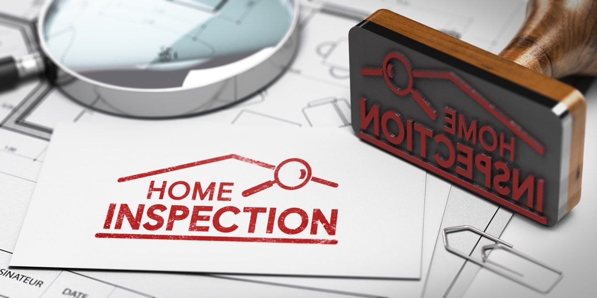 A wooden rubber stamp and magnifying glass sit on architectural blueprints next to a paper reading 