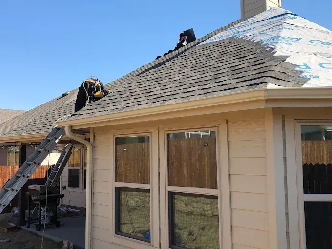 Roofers repairing a house roof on a sunny day.