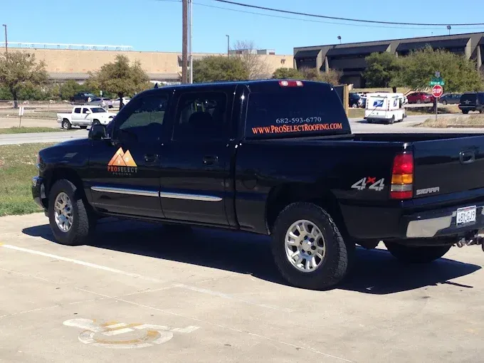 Black pickup truck parked in a parking lot. It has a logo and phone number on the window.
