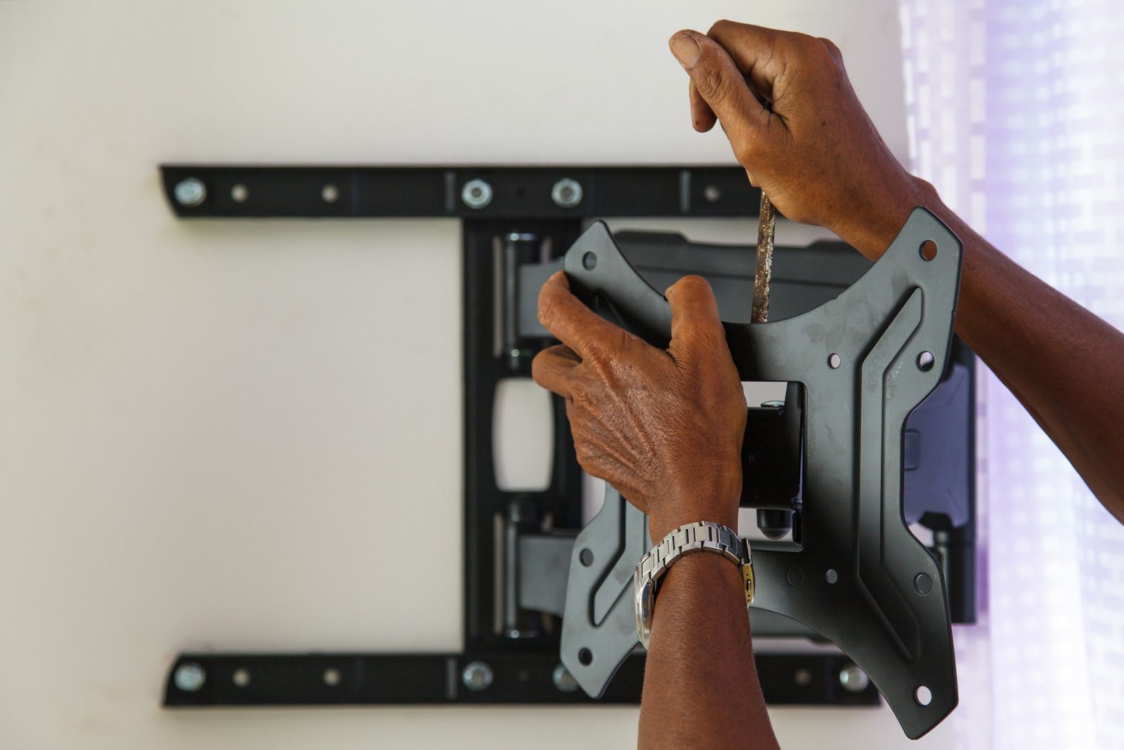 A person is installing a tv mount on a wall.
