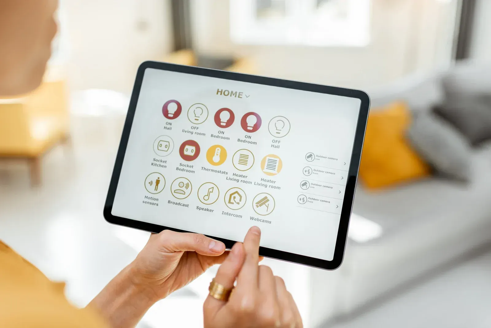 Person using a tablet with a smart home control interface; indoors, touching the screen.