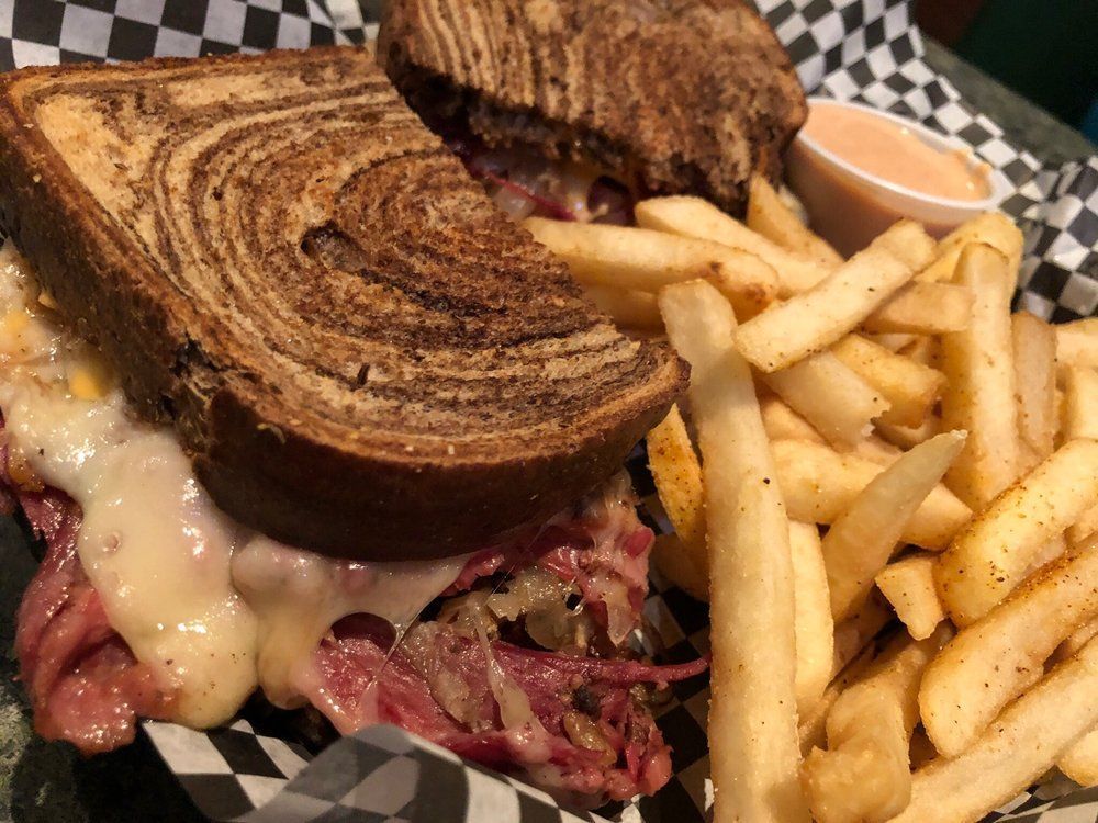 A sandwich and french fries are on a checkered table cloth.