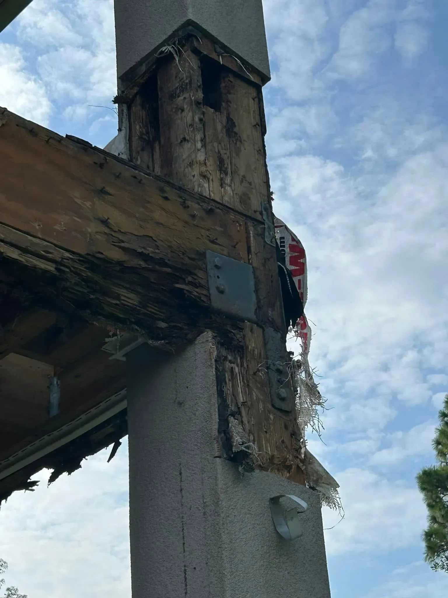 A concrete pole with a wooden beam attached to it.