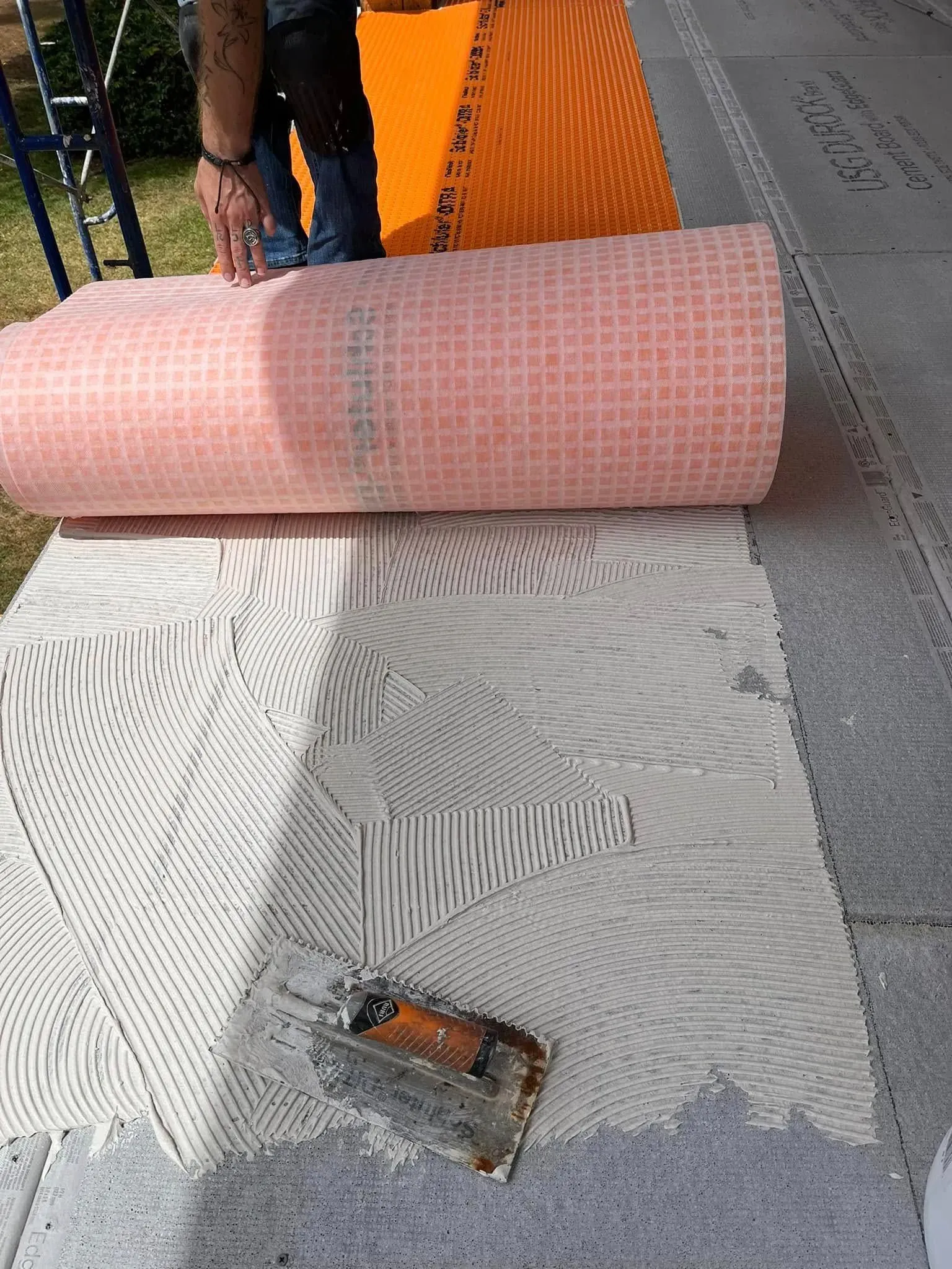 A man is laying a roll of tile on the floor.