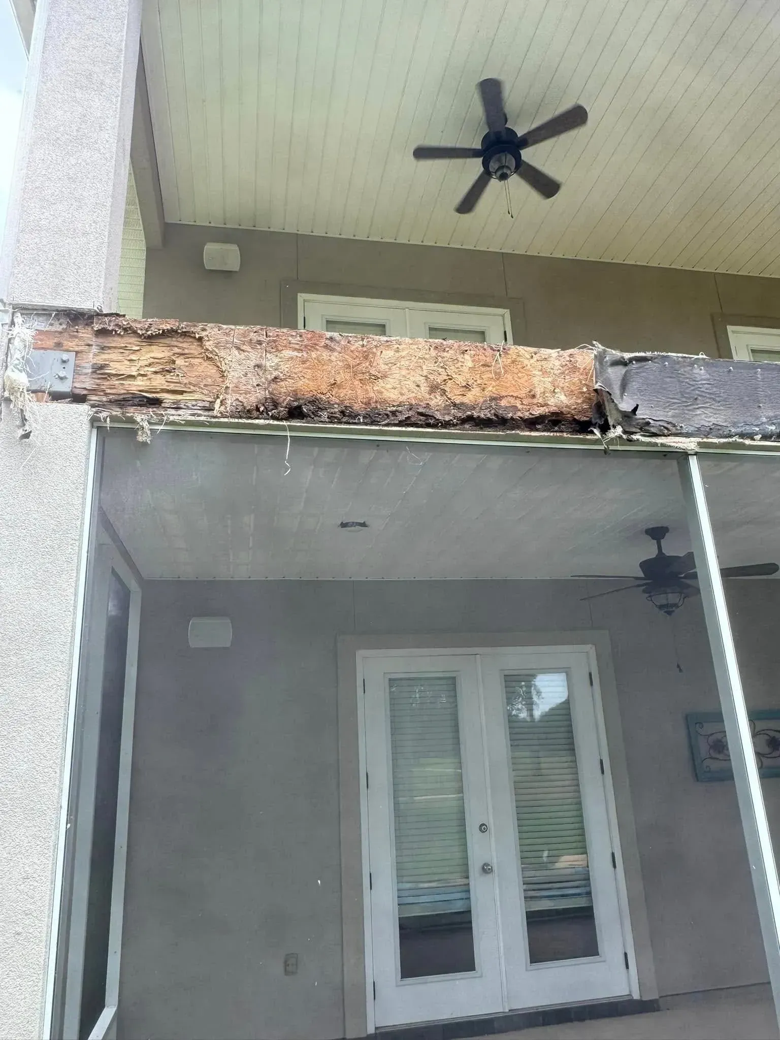 A ceiling fan is hanging from the ceiling of a porch.
