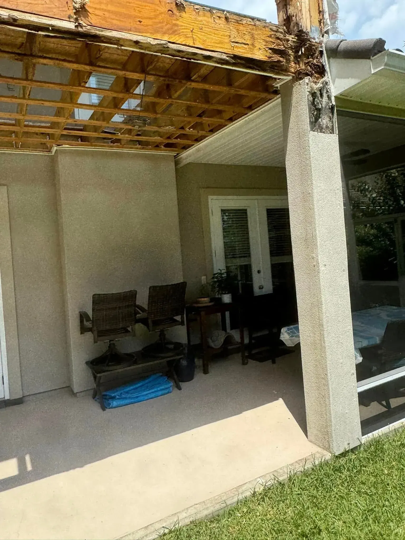 A patio with a wooden roof and a table and chairs on it.