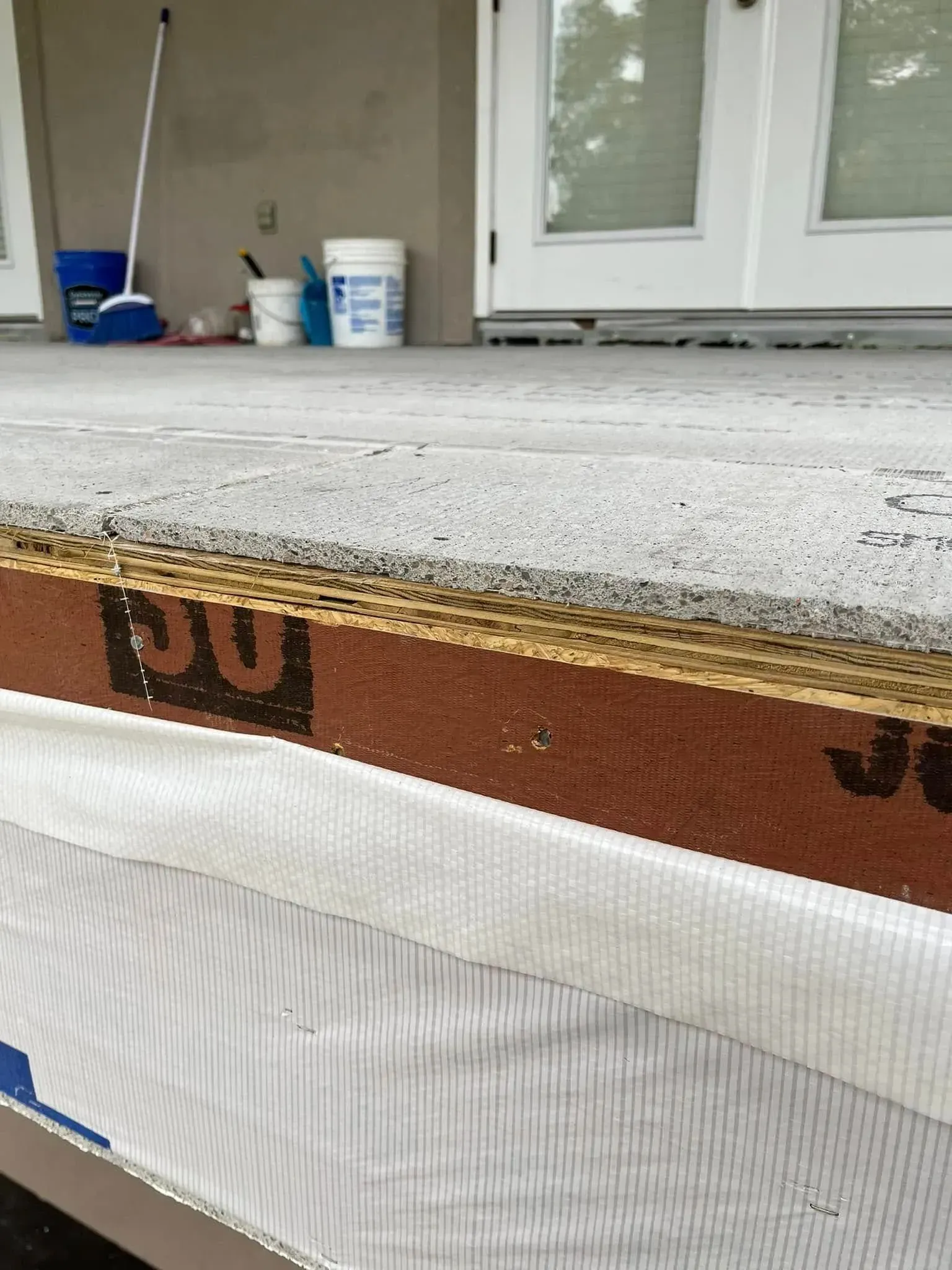 A close up of a porch with a broom and buckets in the background.