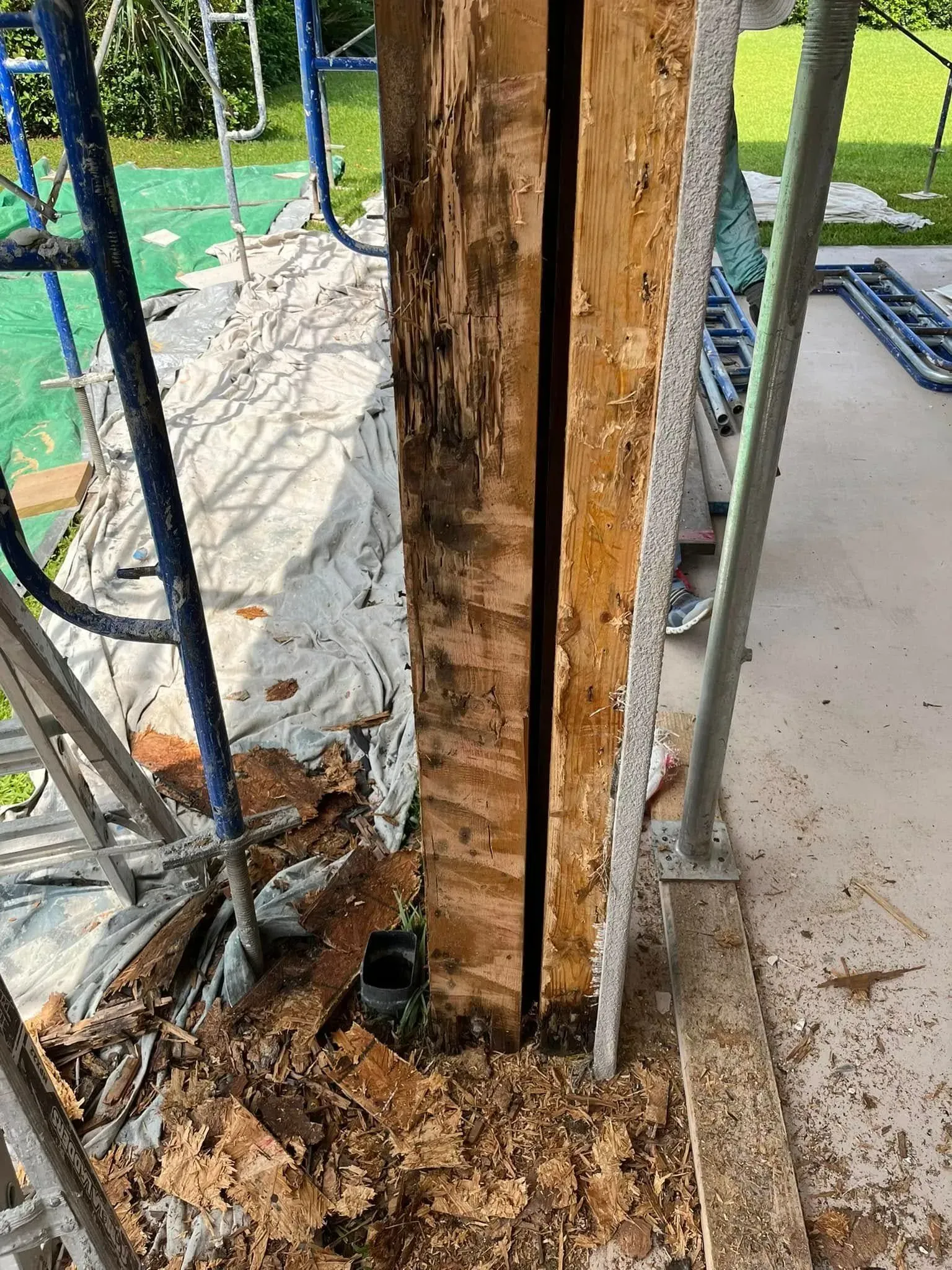 A wooden post with a hole in it is being removed from a building.