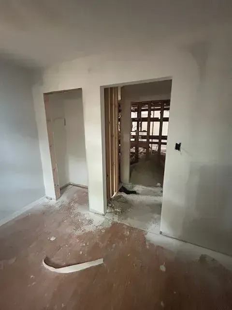 An empty room with a doorway leading to a room in a house under construction.