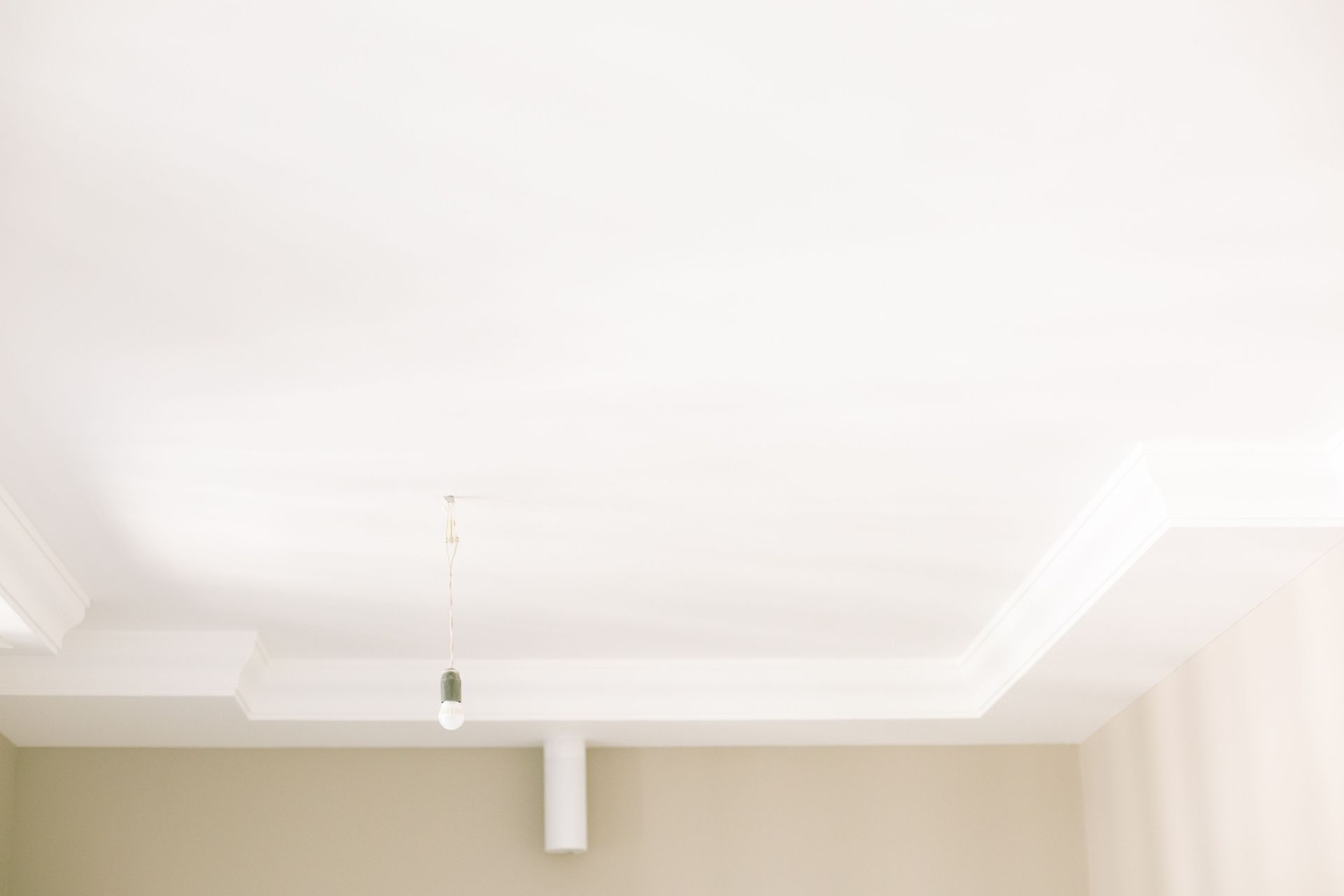 Ceiling with recessed tray detail, cream walls, and a hanging light fixture