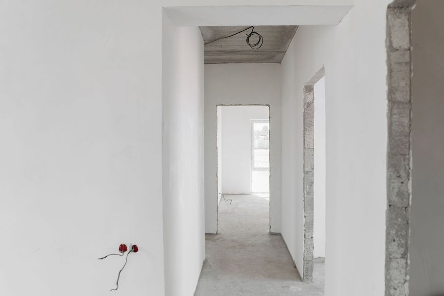 Unfinished white hallway with doorways and exposed wiring in a new building