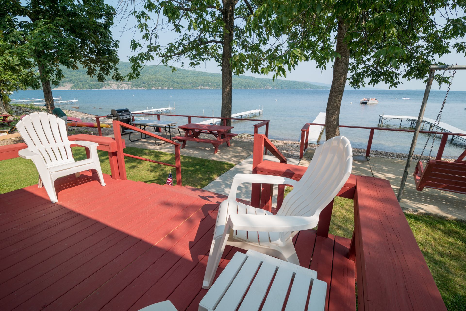 Red lakeside deck with white chairs and table overlooking the water