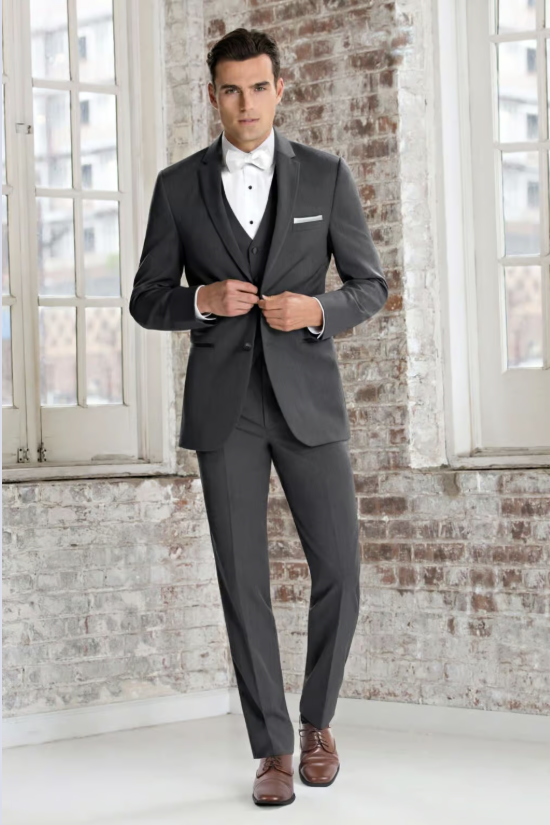 Man in a dark suit adjusting his jacket in a bright studio with large windows