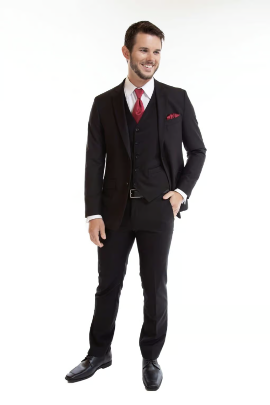 Man in a dark suit with red tie and pocket square, standing against a white background.