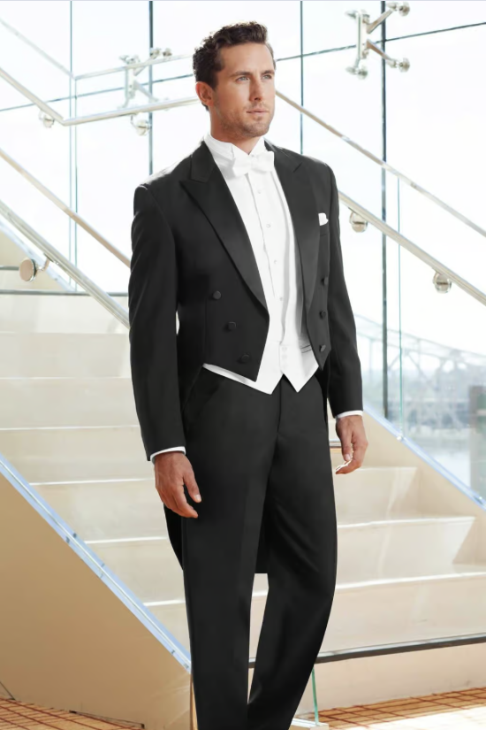 Man in a black tuxedo standing on a staircase in a bright modern interior