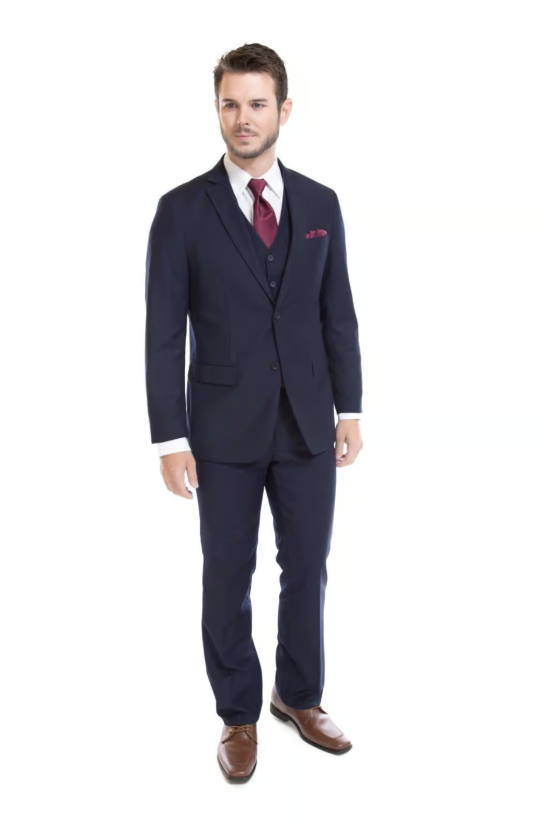 Man in a navy suit with burgundy tie standing against a white background