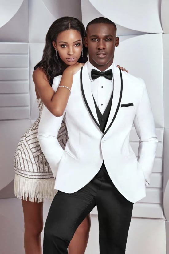 Couple posing in formal white outfits against a geometric silver backdrop