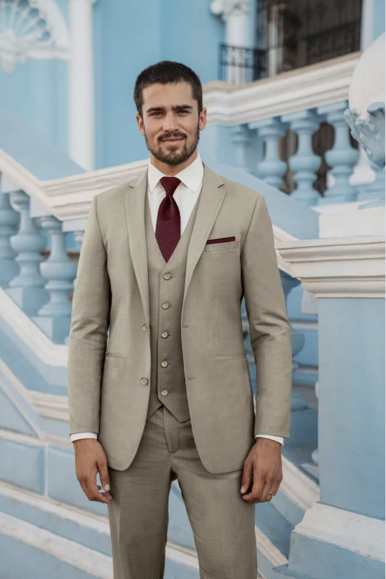 Man in a beige suit standing on blue-and-white steps by an ornate building