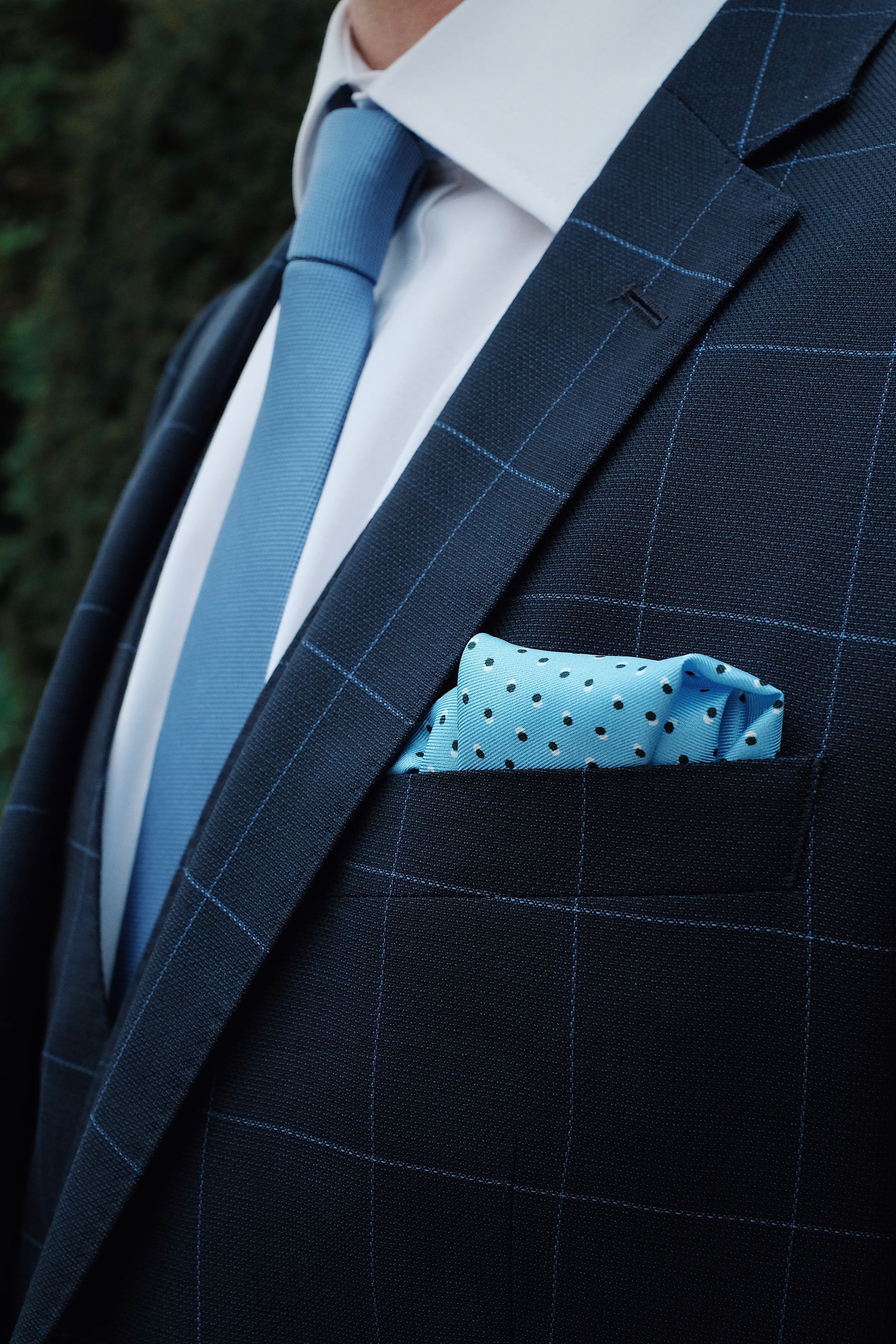 Man in a navy suit with a light blue tie and patterned pocket square