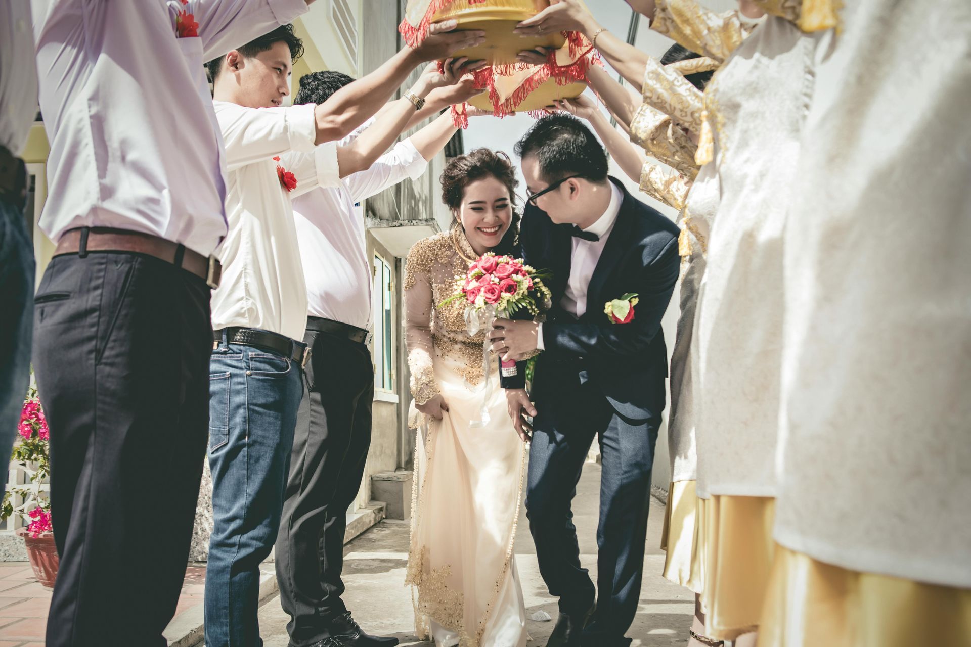 Bride and groom walking through an arch of raised arms at an outdoor wedding ceremony