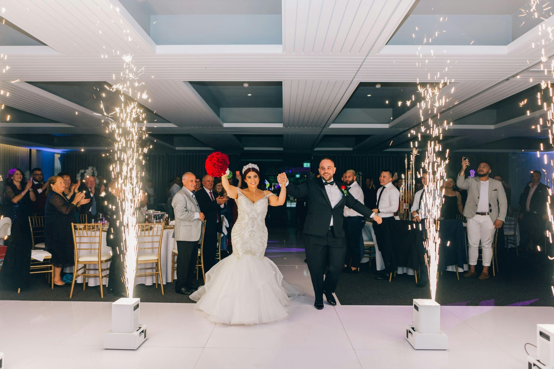 Wedding couple walking through indoor sparklers at a reception entrance