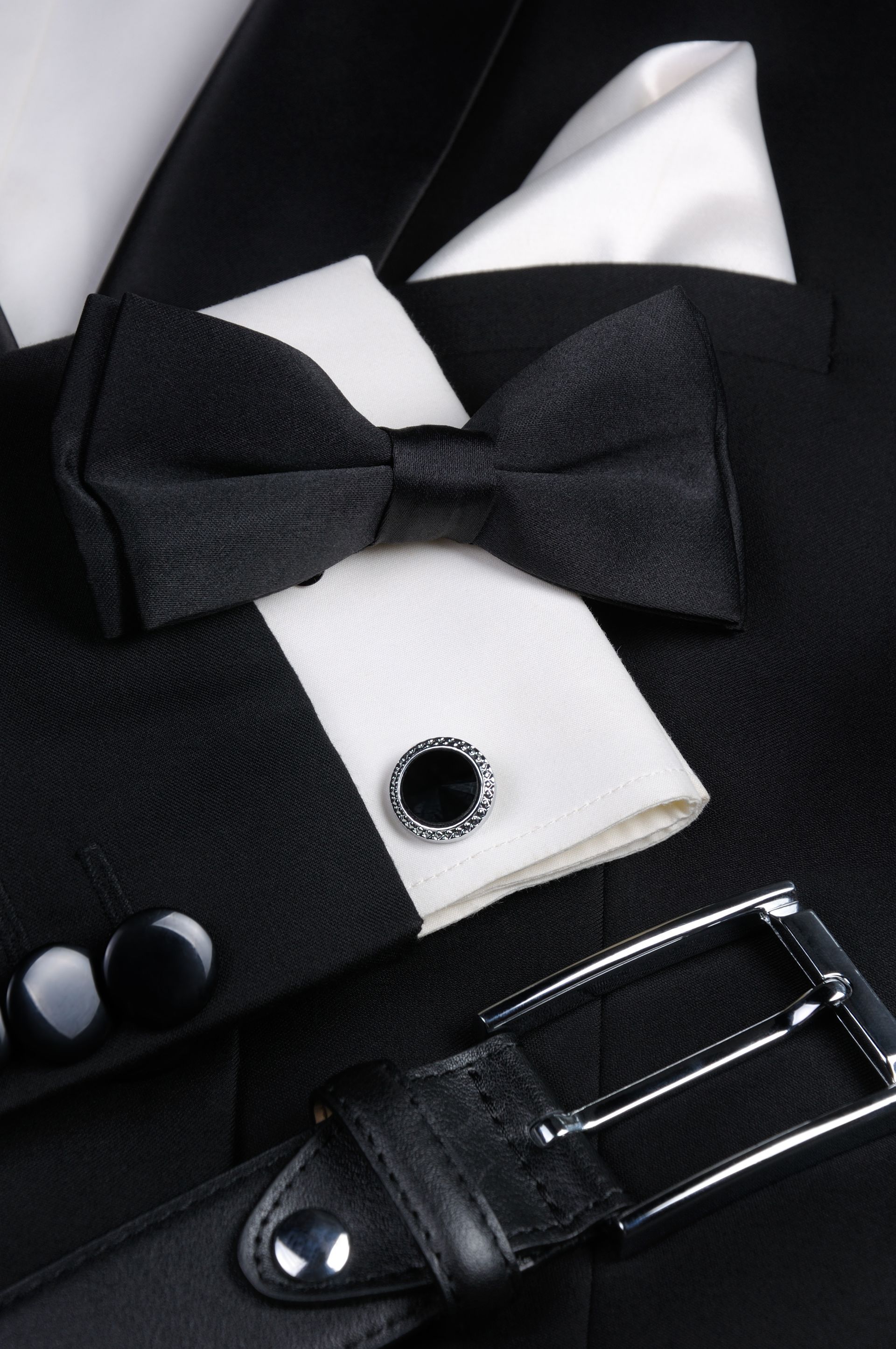 Black tuxedo with bow tie, white shirt, cufflink, and belt buckle close-up