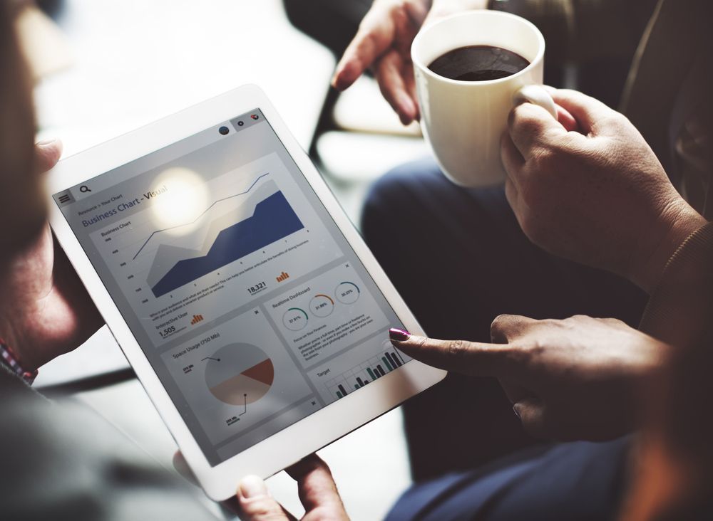 A Person Is Holding A Cup Of Coffee And Looking At A Tablet — NQ Business Advisers In Jensen, QLD