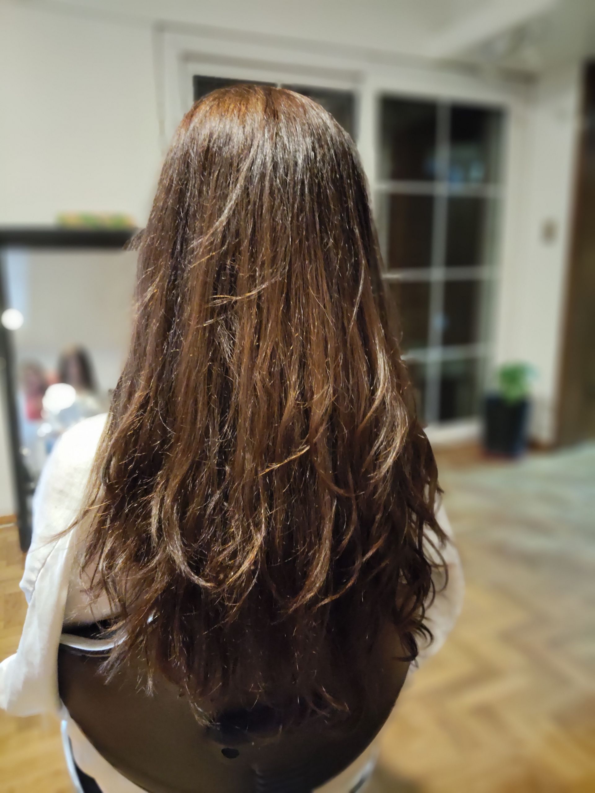 Lavado de cabello en una peluquería, con agua enjuagándose sobre la cabeza de la clienta en el lavabo.