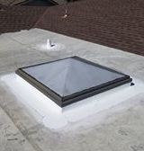 A skylight is sitting on top of a concrete roof.
